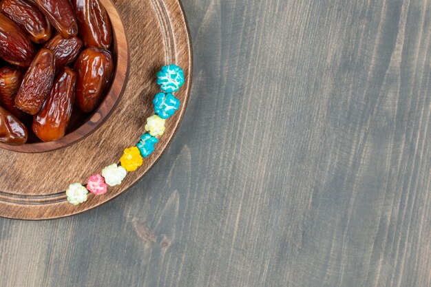 Bowl of dates and popcorns on wooden plate