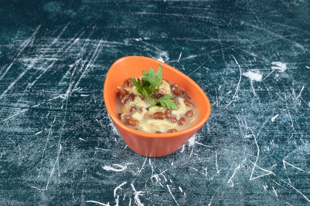 Чаша вкусного супа с макаронами и фасолью на синем фоне. Фото высокого качества