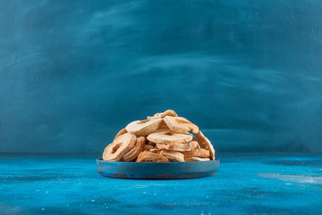 Free photo a bowl of dried apple rings on the blue surface