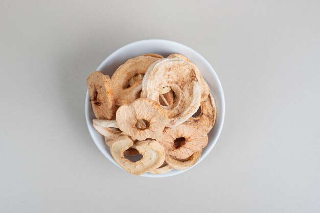 Bowl of dried apple rings on white surface