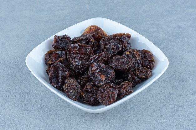 A bowl of dried cherry, on the marble table. 