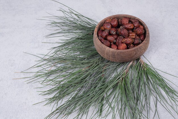 Bowl of dried cranberries and pine branch on marble table. High quality photo