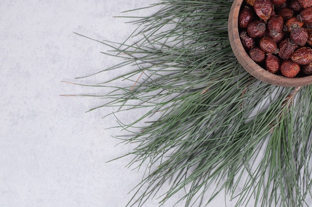 Free photo bowl of dried cranberries and pine branch on marble table. high quality photo