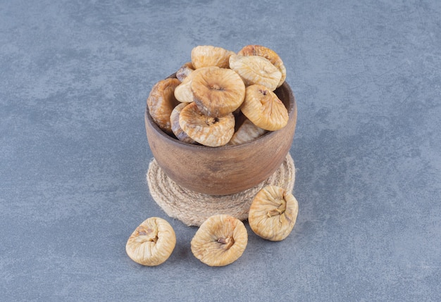 Free photo a bowl of dried fruit on the trivet, on the marble background.