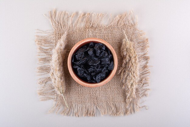 Bowl of dried plum fruits placed on white surface. High quality photo