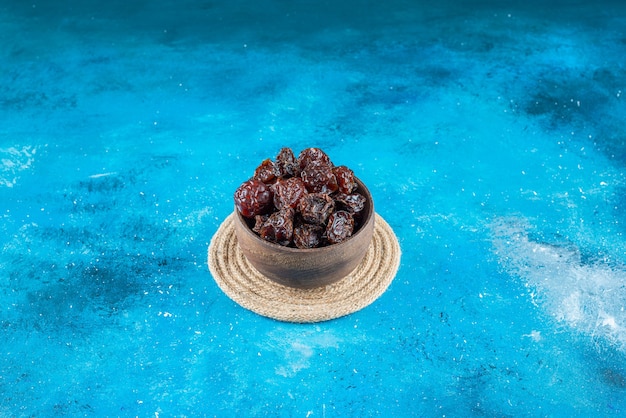 Free photo a bowl of dried plums on a trivet on the blue surface