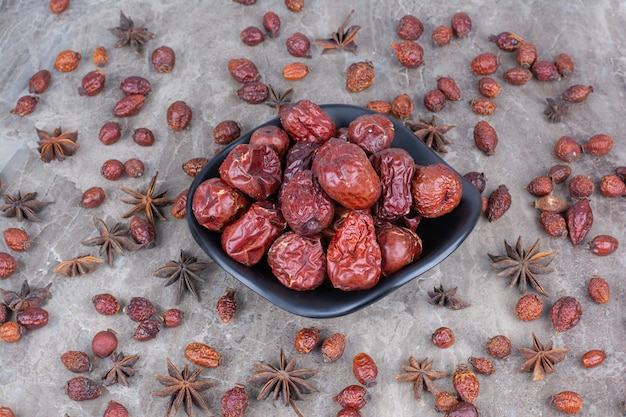 Free photo bowl of dried rosehips on stone background.