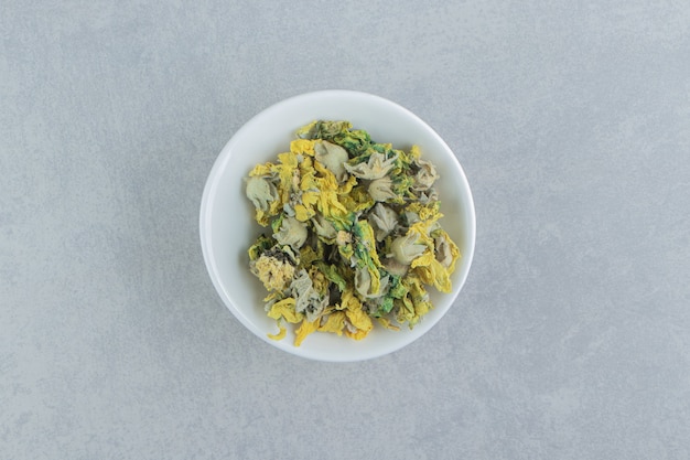 Bowl of dry chrysanthemum flowers on stone surface