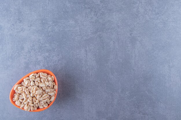 A bowl of dry cornflakes , on the blue background.