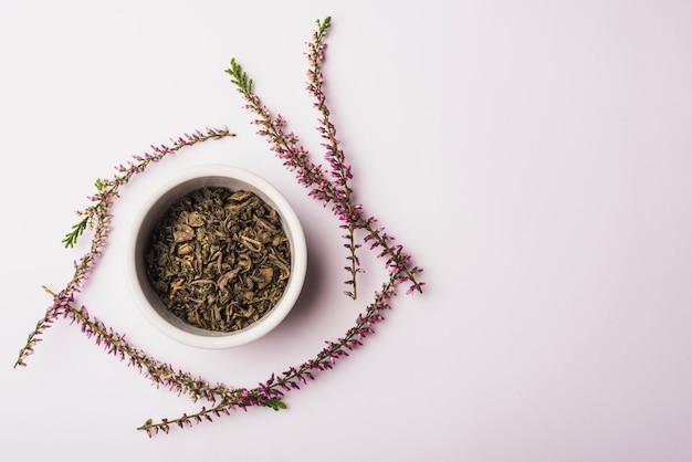 Bowl of dry petals surrounded with lavender flowers on white background