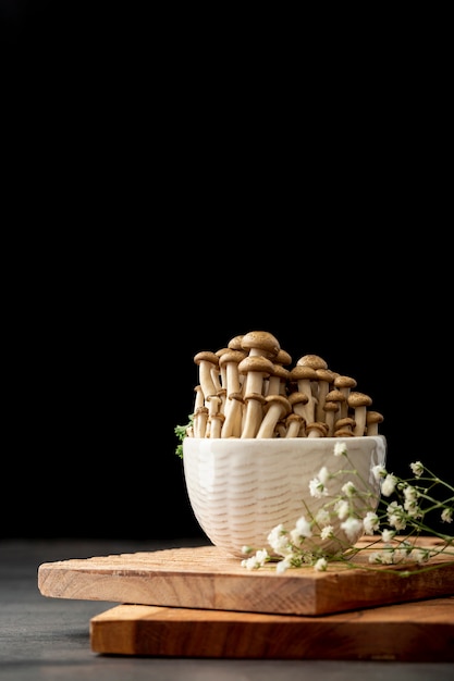 Free photo bowl filled with mushrooms on a wooden support