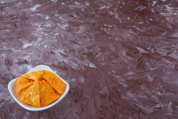 A bowl of flavorful spicy chips on the marble surface