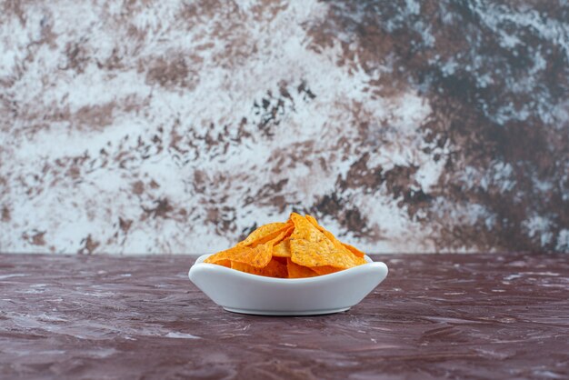 A bowl of flavorful spicy chips , on the marble table. 