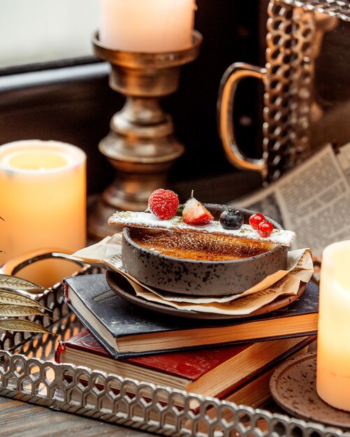 A bowl of french dessert garnished with berries placed on the book