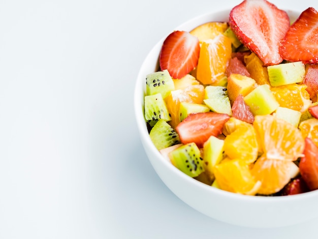Bowl of fresh fruit bright salad on white background
