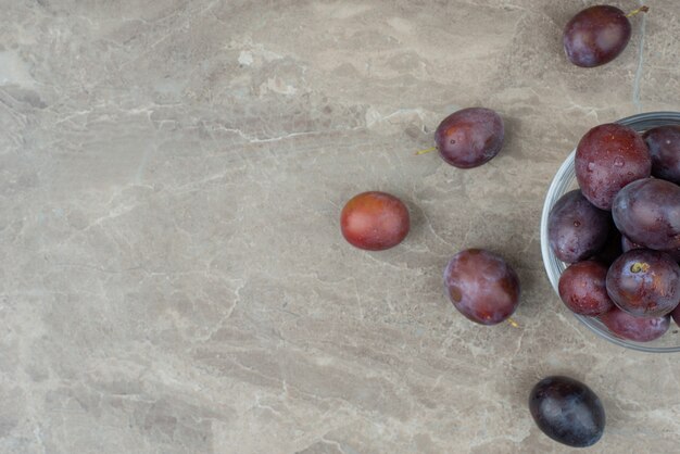 Bowl of fresh plums on marble.