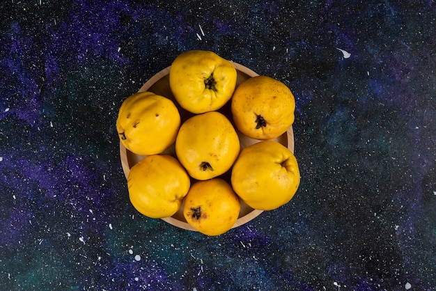 Free photo bowl of fresh quince fruits placed on dark table.