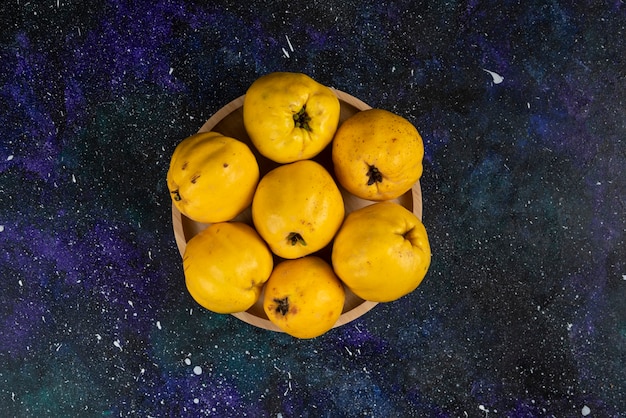 Foto gratuita ciotola di mele cotogne fresche poste sul tavolo scuro.