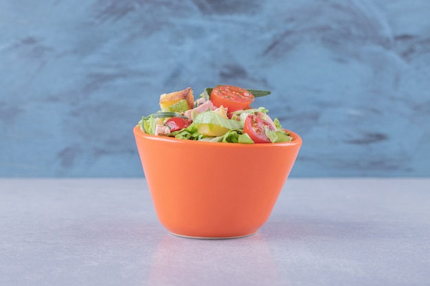 Bowl of fresh salad with sausages on marble background. 