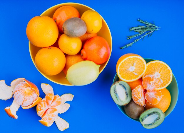 フルーツレモンのボウル。オレンジ色の果物とキウイ青い背景