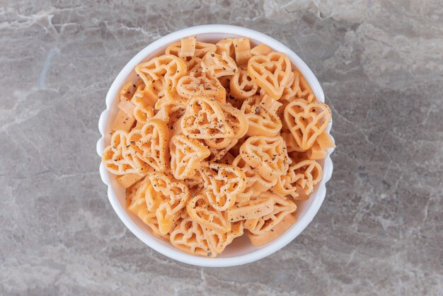 Bowl full of different shaped pasta , on the marble surface.