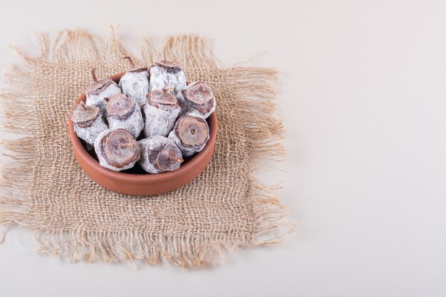 Bowl full of dried persimmons and burlap on white background. High quality photo