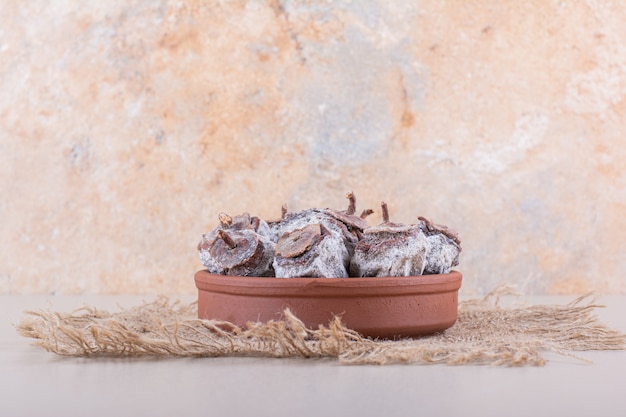 Bowl full of dried persimmons and burlap on white background. High quality photo