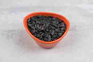 Бесплатное фото Чаша, полная черных семян подсолнечника, помещенная на каменный стол.