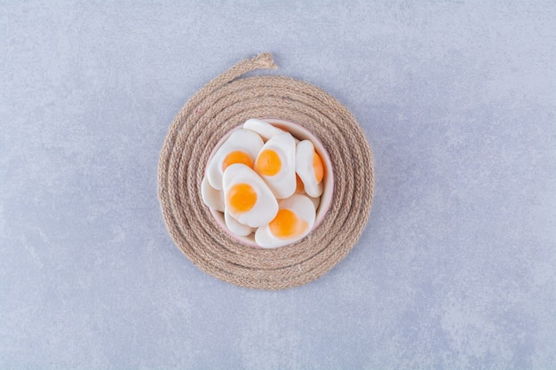Foto gratuita una ciotola piena di uova fritte in gelatina dolci su un cilicio.