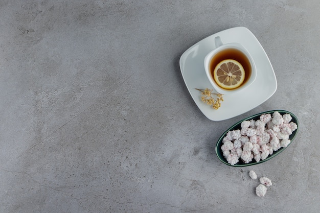 石のテーブルの上に熱いお茶のガラスのカップと甘い白いキャンディーでいっぱいのボウル。