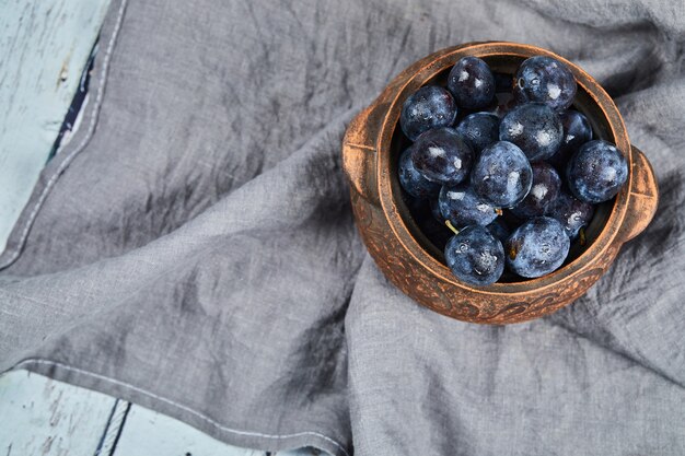 A bowl of garden plums on gray tablecloth. 