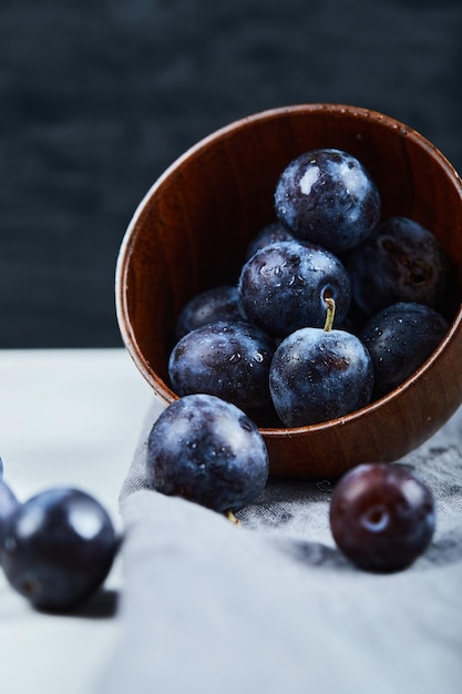 Bowl of garden plums on white and black.