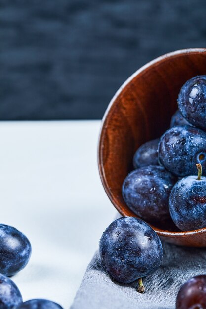 Bowl of garden plums on white and dark background. High quality photo