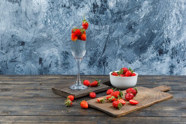Bowl, glass and cutting board with strawberries