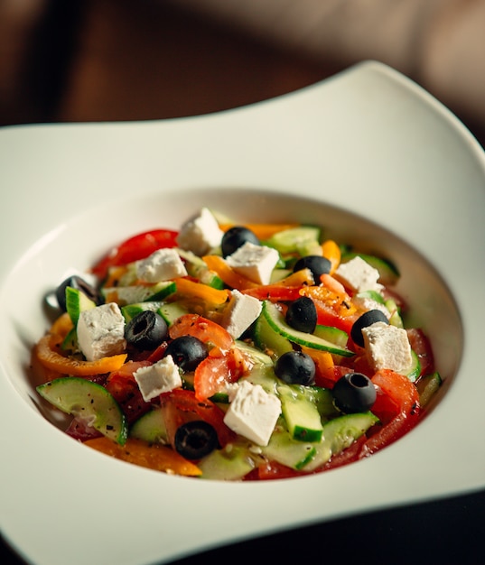 A bowl of greek salad with tomato, cucumber, white cheese, olive