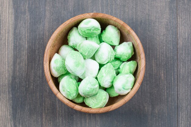 Чаша зеленых конфет на деревянной поверхности