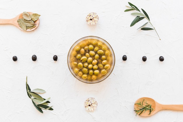 Bowl of green olives decorated with herbs and garlic bulbs