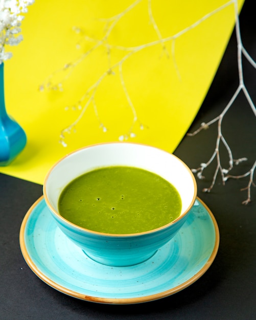 A bowl of green vegetable soup in turquoise ceramic bowl