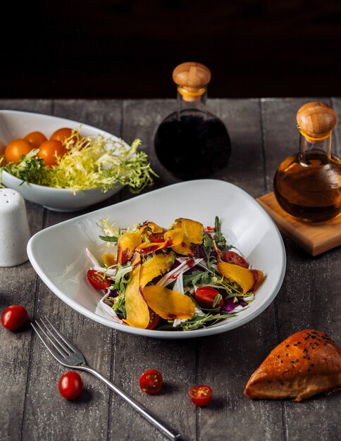 A bowl of gresh vegetable salad served with pomegranate sauce and oil