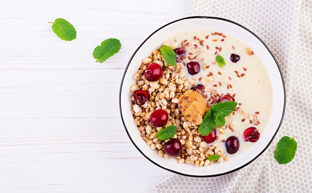 Bowl of homemade granola with banana mashed, peanut butter and fresh berries