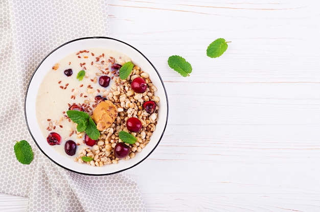 Bowl of homemade granola with banana mashed, peanut butter and fresh berries