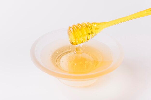 Bowl of honey and dipper on white background