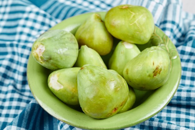 A bowl of juicy green figs on blue tablecloth.