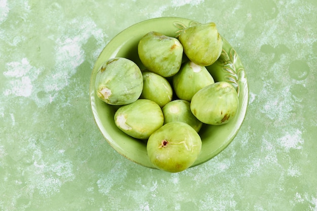 Free photo a bowl of juicy green figs on green.