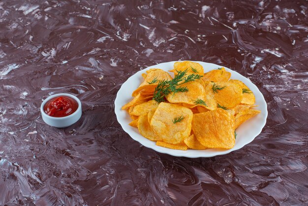 Foto gratuita una ciotola di ketchup e patate fritte in un piatto sulla superficie di marmo