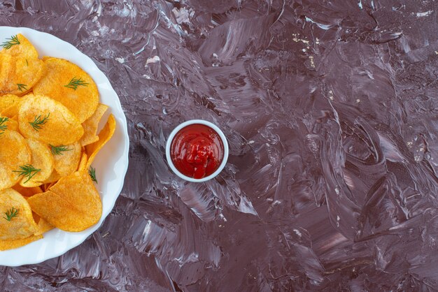 A bowl of ketchup and potato fries in a plate, on the marble table. 