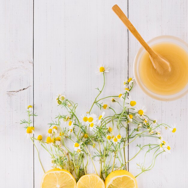 Bowl of lemon curd; chamomile flowers and lemon on wooden plank
