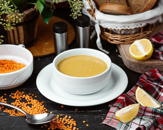 Foto gratuita scodella di zuppa di lenticchie servita con fettine di limone