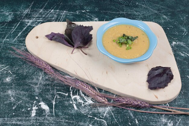 Ciotola di zuppa di lenticchie con basilico su tavola di legno.