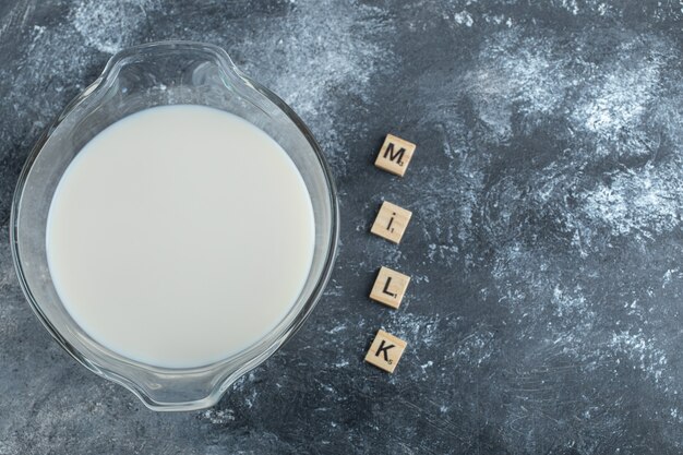 Bowl of milk and wooden letters spelled as milk.